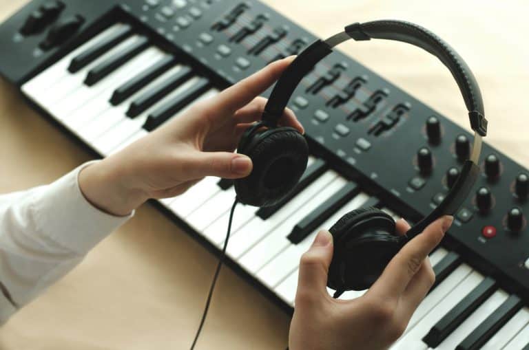 Woman holding headphones over her digital piano